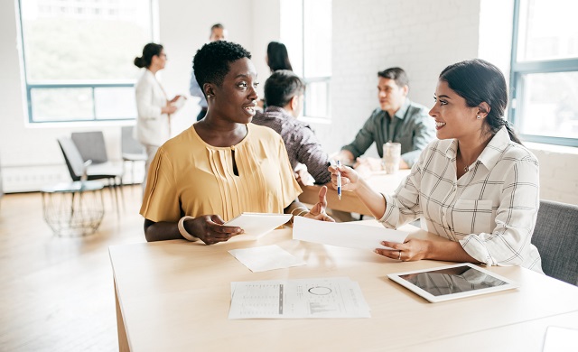 Two women sitting at a table discussing financial documents