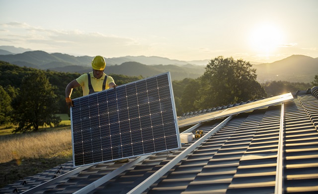 Un homme installant des panneaux solaires sur un toit