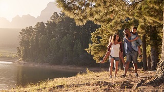 Un couple et un enfant se promènent au bord du lac.